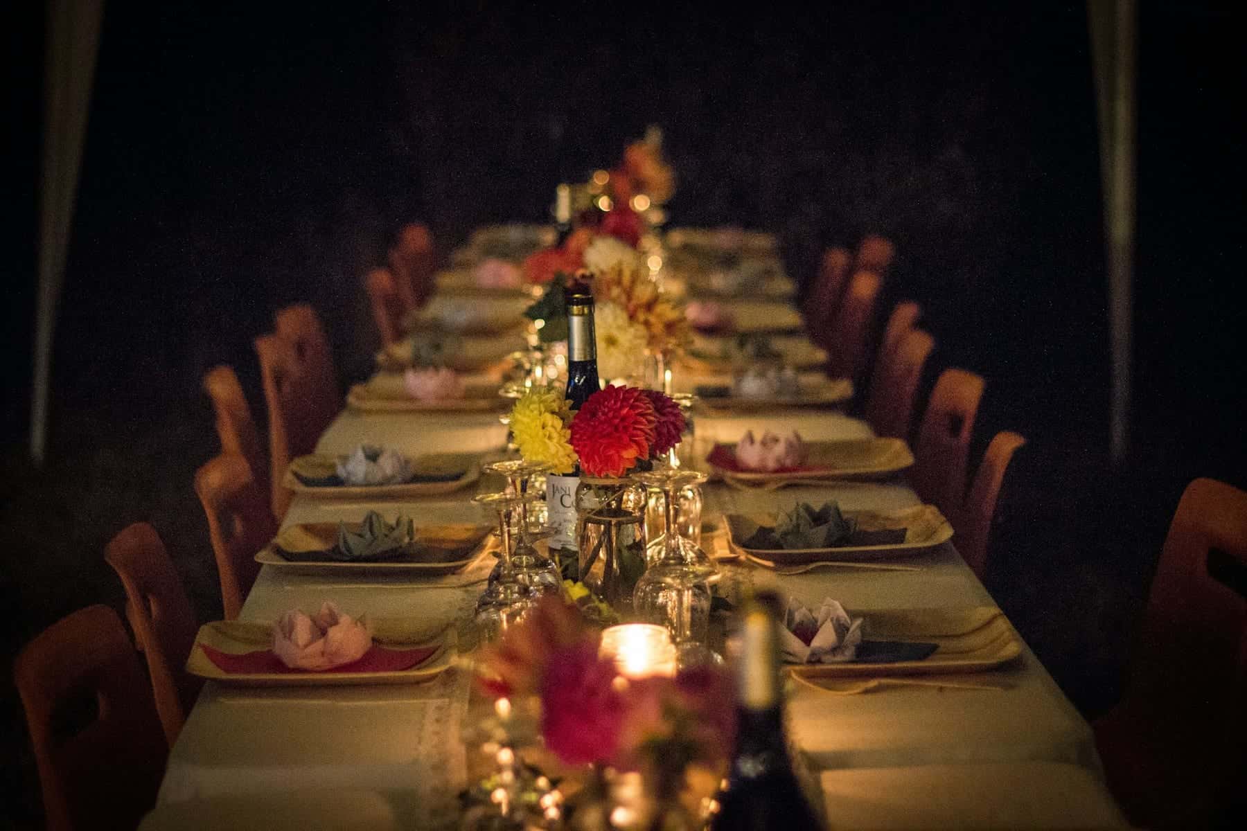 Long dinner table set with candles, flowers and glassware for a celebration